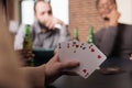 Selective focus shot of woman holding cards in hand while playing with friends at home. Royalty Free Stock Photo