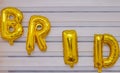 A selective focus shot of the word `bride` made of golden balloons on a wall.