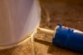 Selective focus on silicone caulking ready to be applied around the seal of a bathroom toilet.