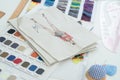 Selective focus on sketch of creative fashion clothes on paper, with fabric and threads color chart, tailor tools on working desk Royalty Free Stock Photo