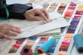 Selective focus on sketch of creative fashion clothes on paper on hands of fashion designer, with fabric and threads color chart, Royalty Free Stock Photo