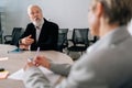 Selective focus of skilled mature adult male team leader in suit talking to diverse ages colleagues on meeting Royalty Free Stock Photo