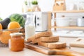 Selective focus on sliced whole wheat bread on wooden tray with apricot jam in jar, bottle of fresh milk, oranges, avocado Royalty Free Stock Photo