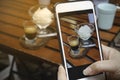 Blogger food with smartphone picture which woman hand holding phone taking photo of stylish flat lay ice cream in the cafe and Royalty Free Stock Photo