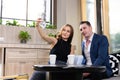 Selective focus at smartphone. Young Caucasian couple dating inside of the coffee shop while women taking selfie photo from mobile Royalty Free Stock Photo