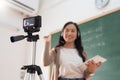 Selective focus, Smiling Asian Young woman teacher teaching and recording video with digital camera Royalty Free Stock Photo