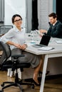 Selective focus of smiling businesswoman in eyeglasses looking at camera in office Royalty Free Stock Photo