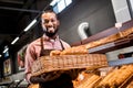 selective focus of smiling male african american shop assistant in apron holding loaves of bread Royalty Free Stock Photo