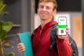 Selective focus. Smiling student boy holding vaccination passport on mobile device. Back to university, school, college