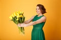 selective focus of smiling woman presenting bouquet of yellow tulips to someone