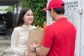 Selective Focus of smiling woman receiving a grocery bag from the courier