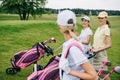 selective focus of smiling women in caps with golf equipment