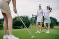 selective focus of smiling women in caps with golf equipment looking at friend playing golf