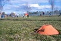 Selective focus on a soccer practice field cone on grass with blurred kids in the background Royalty Free Stock Photo