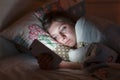 Young sleepy tired woman lying in bed using smartphone at late night, can not sleep. Royalty Free Stock Photo