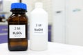 Selective focus of sodium hydroxide base and sulfuric acid solution in brown glass and plastic bottle Royalty Free Stock Photo