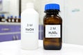 Selective focus of sodium hydroxide base and sulfuric acid solution in brown glass and plastic bottle Royalty Free Stock Photo