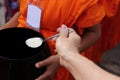 Selective focus on spoon. Hands of people while put food to a Buddhist monk`s alms bowl in Songkran festival Day Royalty Free Stock Photo