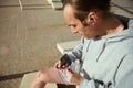 Selective focus on a sportsman holding earphones and smartphone, relaxing after outdoors workout