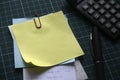 Selective focus of a stack of empty memo notes with payment receipt,pen and calculator on green square background. Copy space for