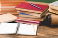 Focus of stacks of books, notebooks, pens, smartphone and disposable cup on wooden surface Royalty Free Stock Photo