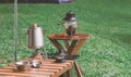 Stainless steel kettle with portable outdoors accessories on wooden table in camping area Royalty Free Stock Photo