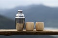 selective focus stainless steel thermal water bottle and bamboo coffee mug placed on a wooden balcony natural mountain background Royalty Free Stock Photo