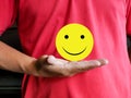 Selective focus sticky note with smiley face symbol hold by a man.