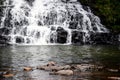 Selective focus on the stone rose up from in a lake and milky water falling from the mountain falling on the dark stone