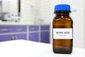 Selective focus of strong Nitric acid solution in brown amber bottle. Blur white laboratory backdrop with copy space.