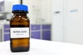 Selective focus of strong Nitric acid solution in brown amber bottle. Blur white laboratory backdrop with copy space. Royalty Free Stock Photo