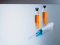 Selective focus. Syringe for injection and two ampoules of coronavirus vaccine and on a silvery aluminum background