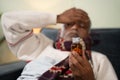 Selective focus on tablet or pills bottle, sick Old man worried about taking pills by placing hand on his head. Royalty Free Stock Photo