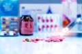 Selective focus on tablets and capsule pills on blurred drug bottle, stainless steel drug tray, blister pack, and paper box of Royalty Free Stock Photo