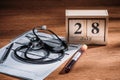 selective focus of test flask with blood sample stethoscope medical questionary and wooden calendar with 28th july date on