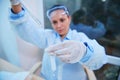 Focus on test tube and graduated lab pipette in a blurred woman scientist hands dripping reagent in research laboratory