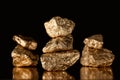 Selective focus of three stacks of gold shiny stones with reflection isolated on black.
