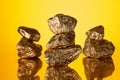 Selective focus of three stacks of gold shiny stones with reflection isolated on yellow .
