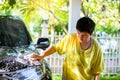 Selective focus to Asian boy washing black car with cloth sponge and shampoo at home