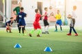 Selective focus to blue marker cones are soccer training equipment on green artificial turf with blurry kid players training backg Royalty Free Stock Photo