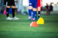 Selective focus to cone marker with blurry soccer team is on green artificial turf Royalty Free Stock Photo