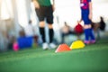 Selective focus to cone marker with blurry soccer team is on green artificial turf Royalty Free Stock Photo