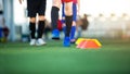 Selective focus to cone marker with blurry soccer team is on green artificial turf Royalty Free Stock Photo