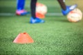 Selective focus to cone marker with blurry soccer team is on green artificial turf Royalty Free Stock Photo