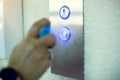 Selective focus to elevator switch button with blur hand of staff cleaning it by alcohol spray in hospital or building office