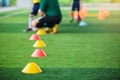 Selective focus to marker cones are soccer training equipment on green artificial turf with blurry coach is training kid players b Royalty Free Stock Photo