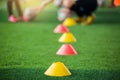 Selective focus to marker cones are soccer training equipment on green artificial turf with blurry coach is training kid players b Royalty Free Stock Photo