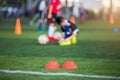 Selective focus to marker cones are soccer training equipment on green artificial turf with blurry kid players training background Royalty Free Stock Photo