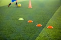 Selective focus to marker cones are soccer training equipment on green artificial turf with blurry kid players training background Royalty Free Stock Photo