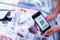 Selective focus to QR code tag on smartphone with blurry frozen food at supermarket